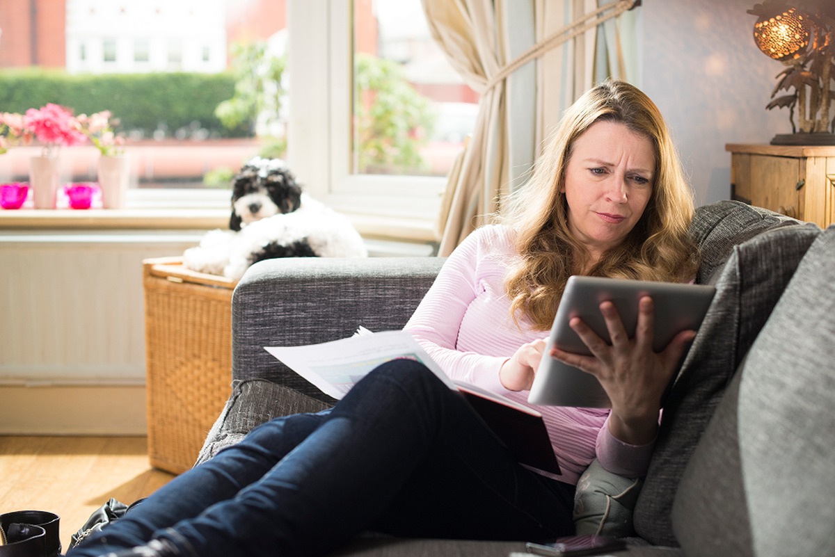 woman on tablet lying on sofa with dog