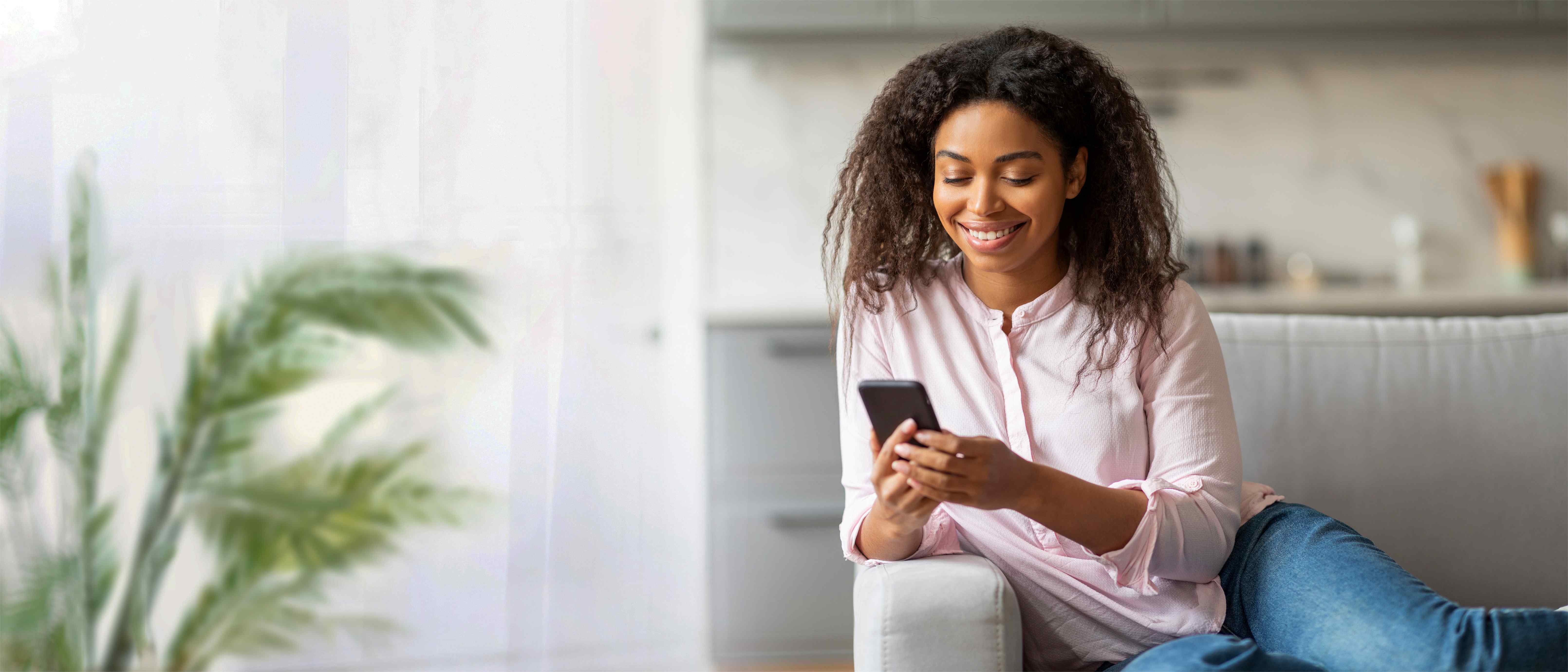 Smiling Woman Using Smartphone on Couch in Modern Living Room