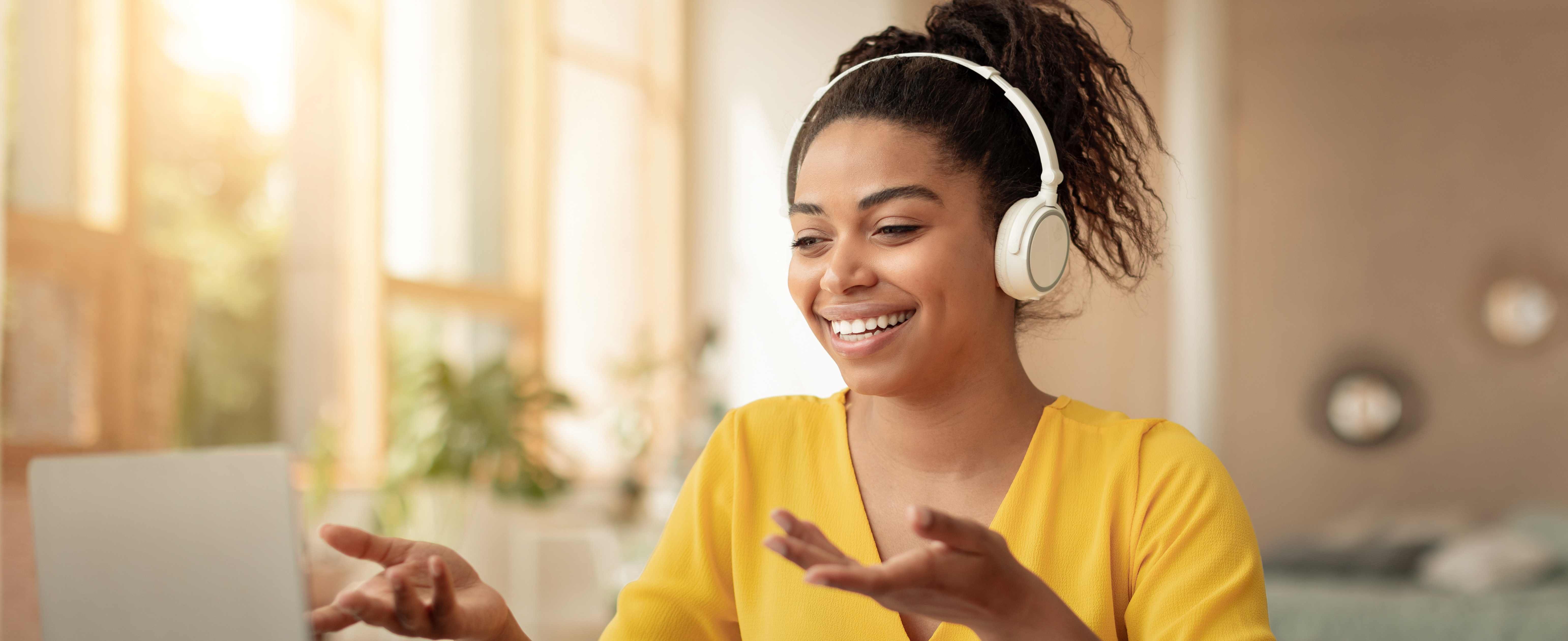 Smiling Young Black Woman Wearing Headphones Engaged In Video Call At Home, Business Concept