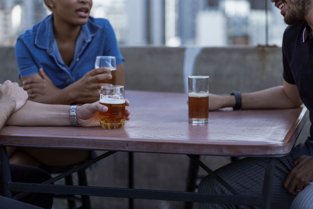 Friends drinking beer together at an outdoor table on a rooftop