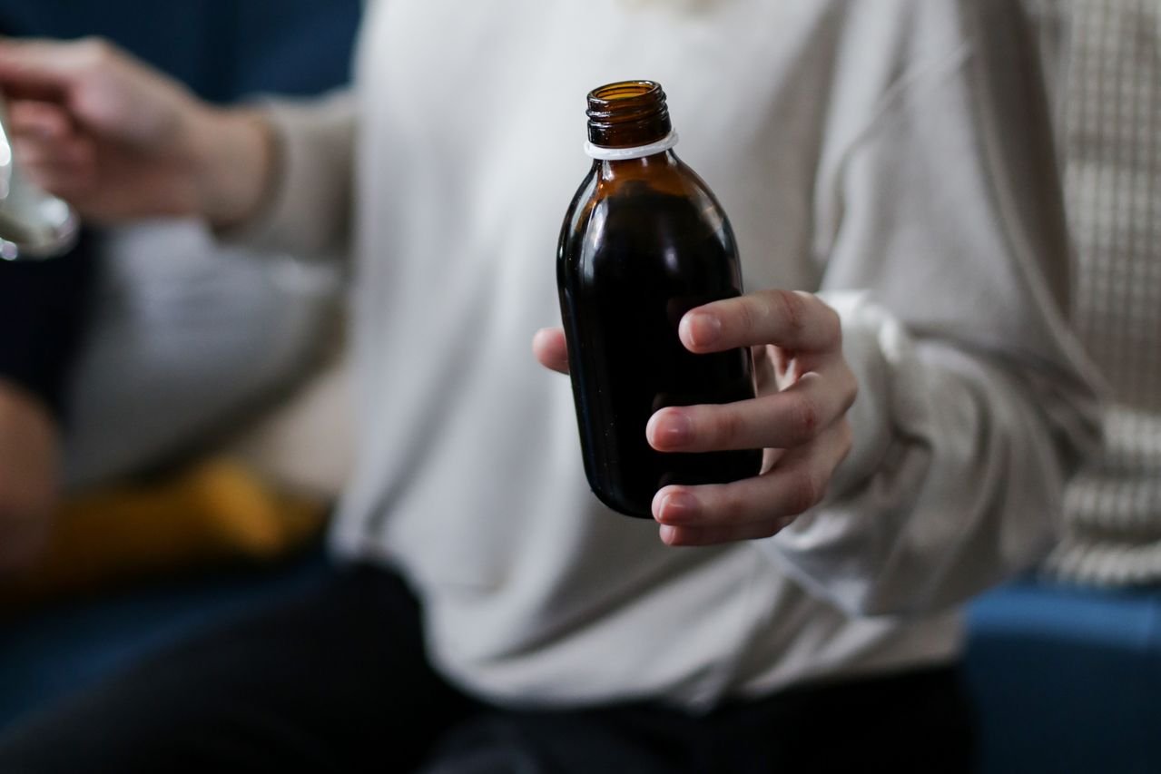 Close-up of a hand holding a brown medicine bottle