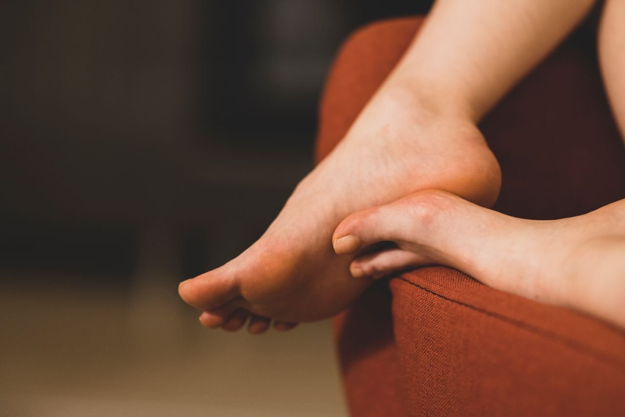 Close-up of bare feet crossed and resting on the arm of a sofa