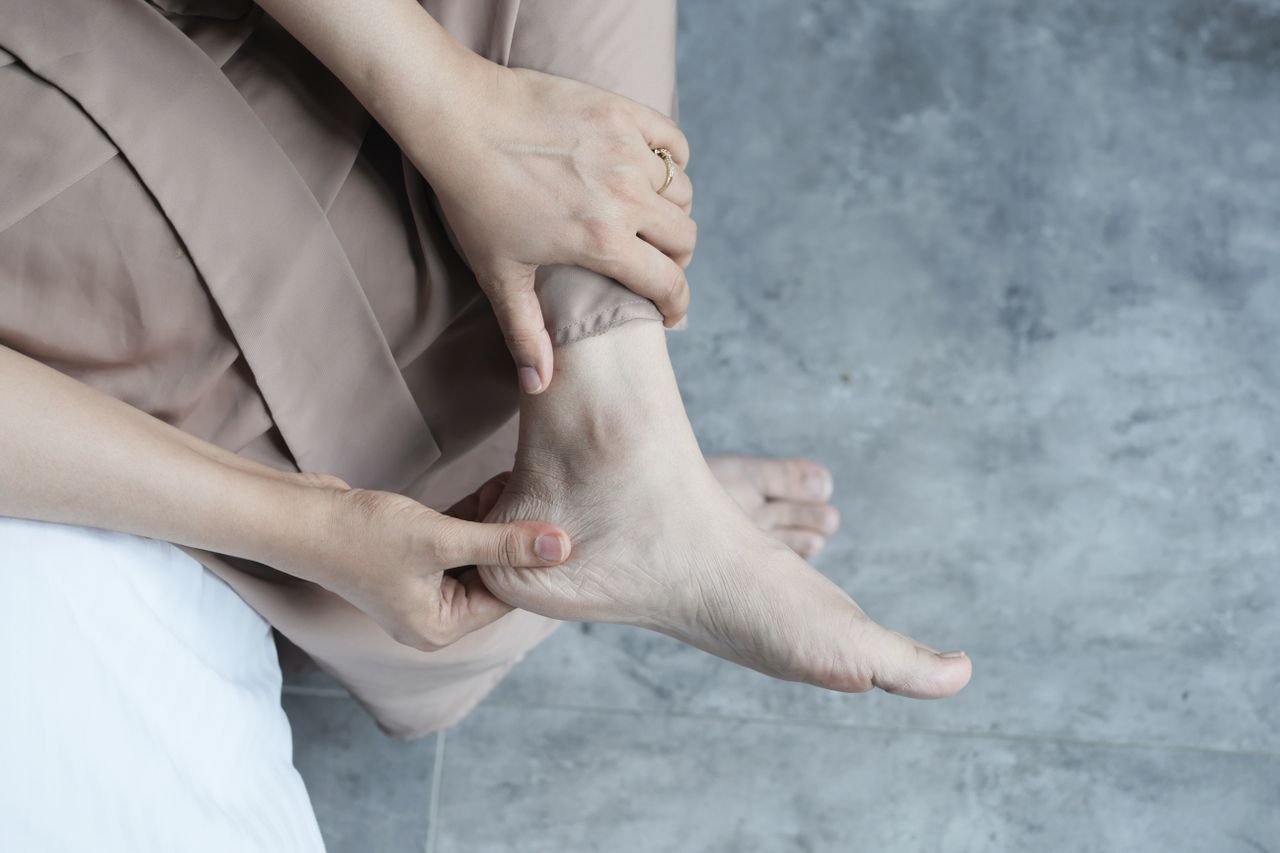 Close-up of hands massaging a swollen, bruised ankle