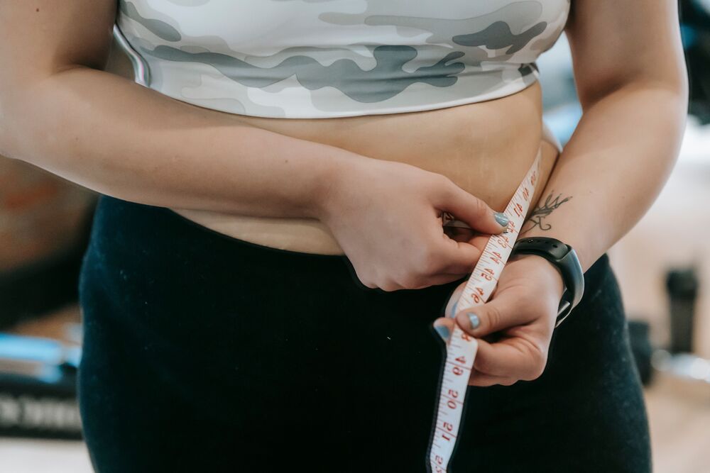 Close-up of a woman measuring her waist with a tape measure