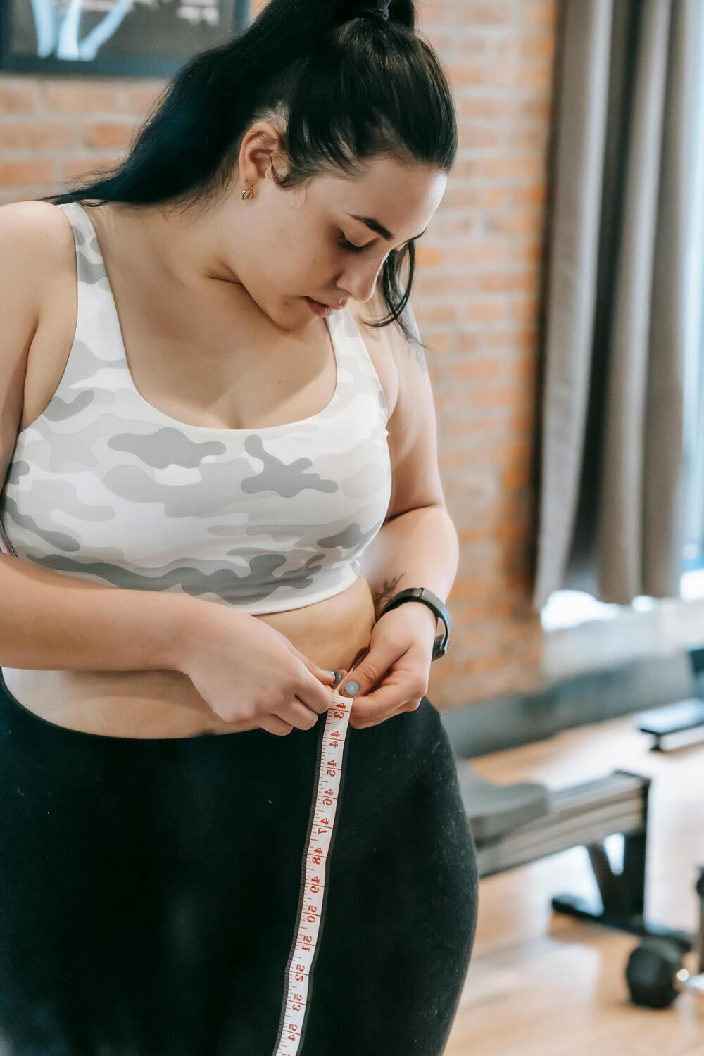 Close-up of a woman measuring her waist with a tape measure