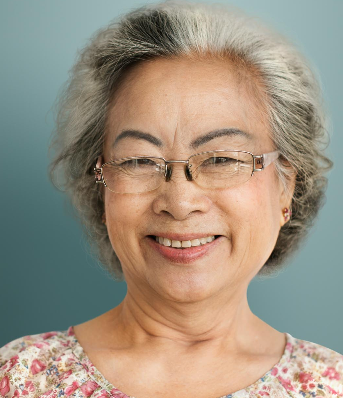 Women with glasses and a flowery top standing behind a light blue background