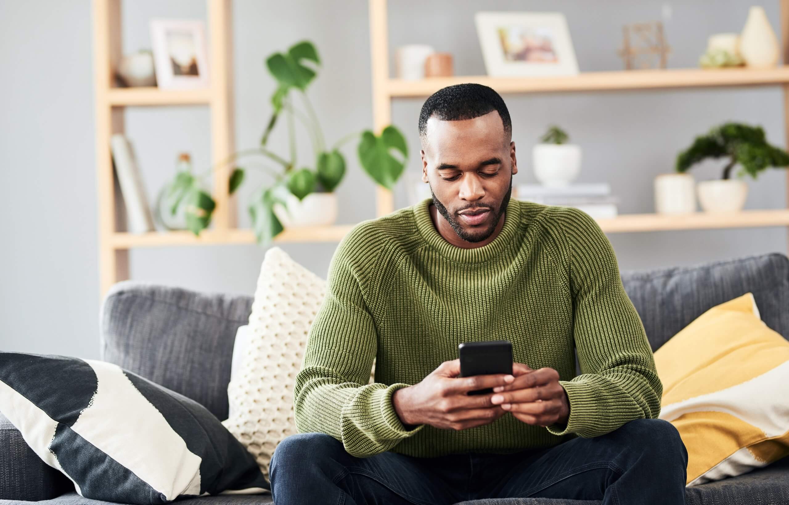 Man sitting on a sofa at home checking his phone