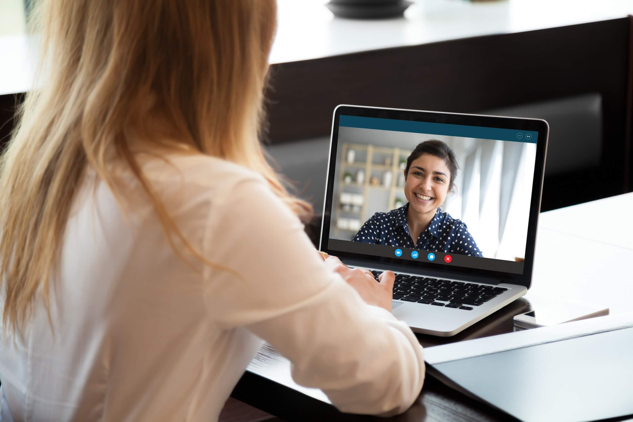 A woman video calling on a laptop with another woman, who is smiling, visible on the screen. An orange 'Featured' badge is in the top right corner.