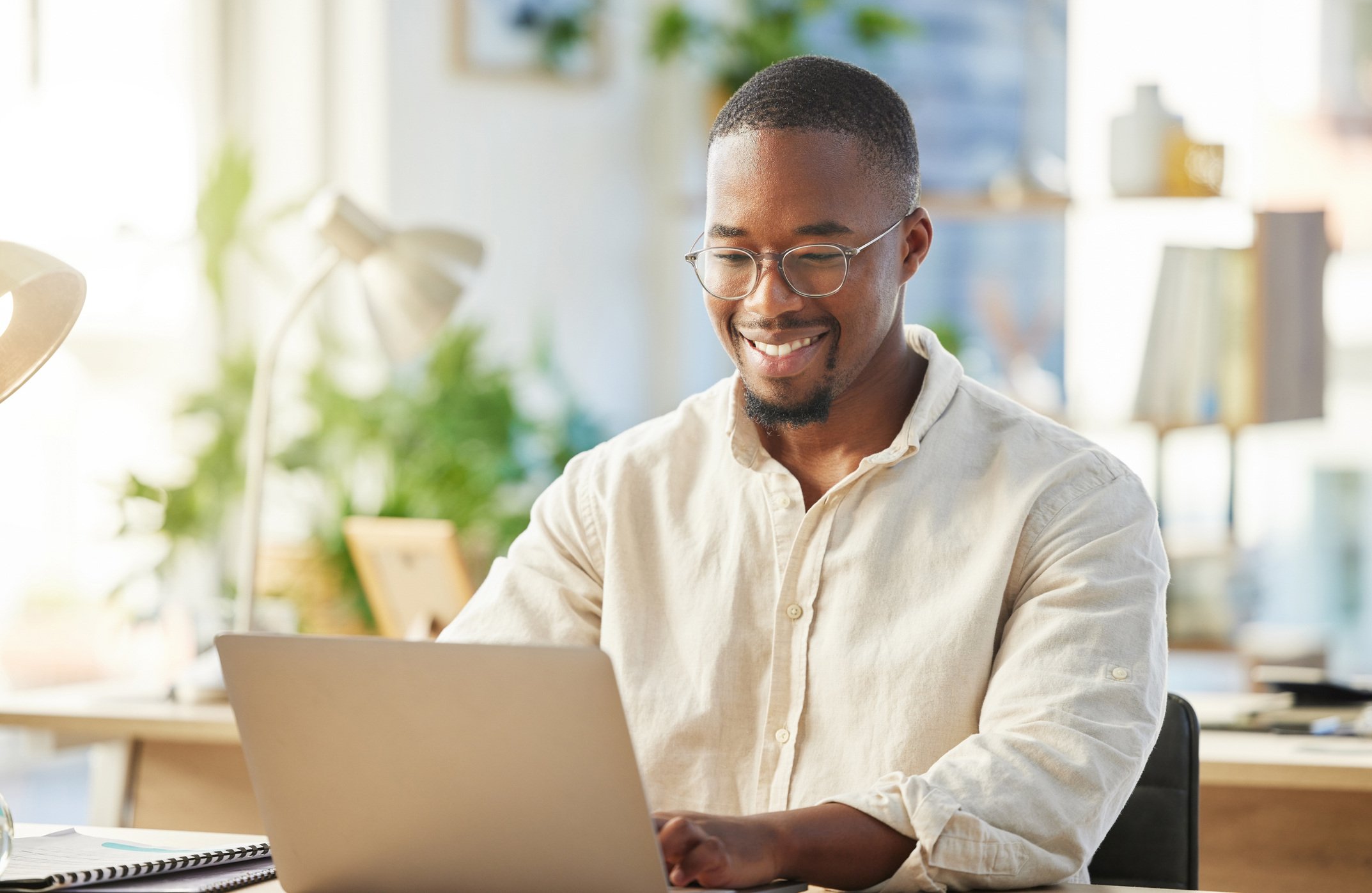 Smiling man working on a laptop at a home desk