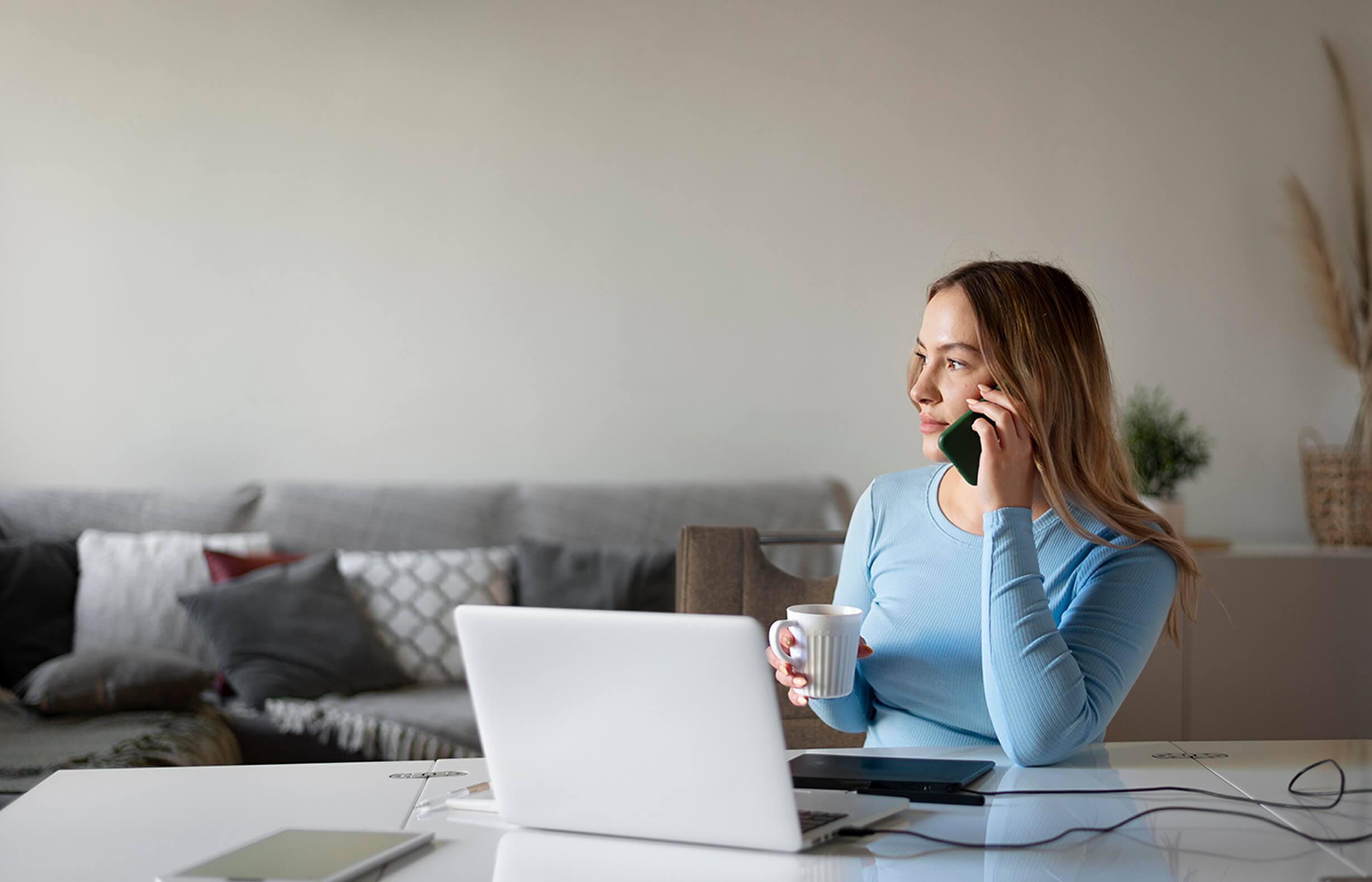 Female presenting person on phone whilst holding mug