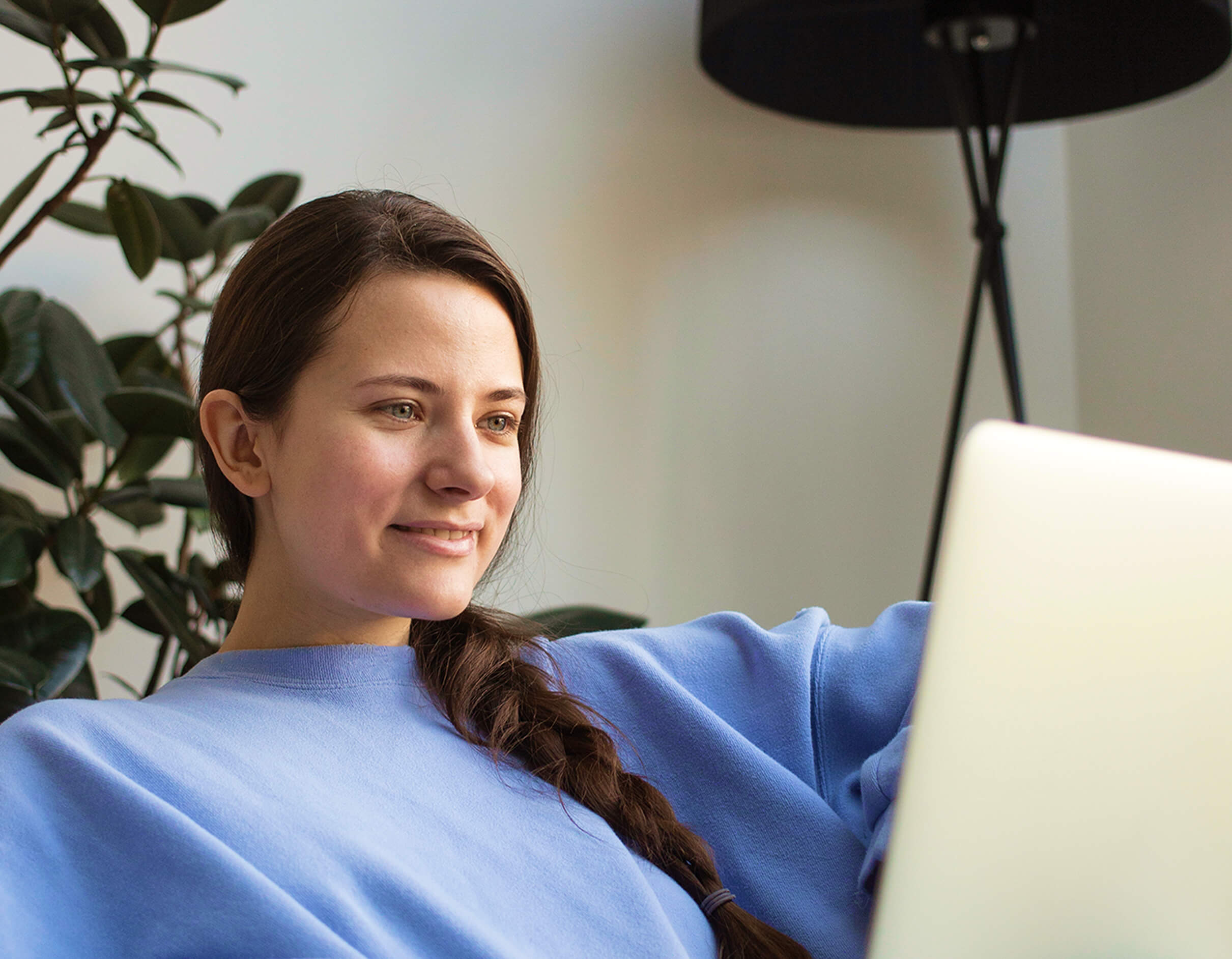 Female presenting person smiling at laptop