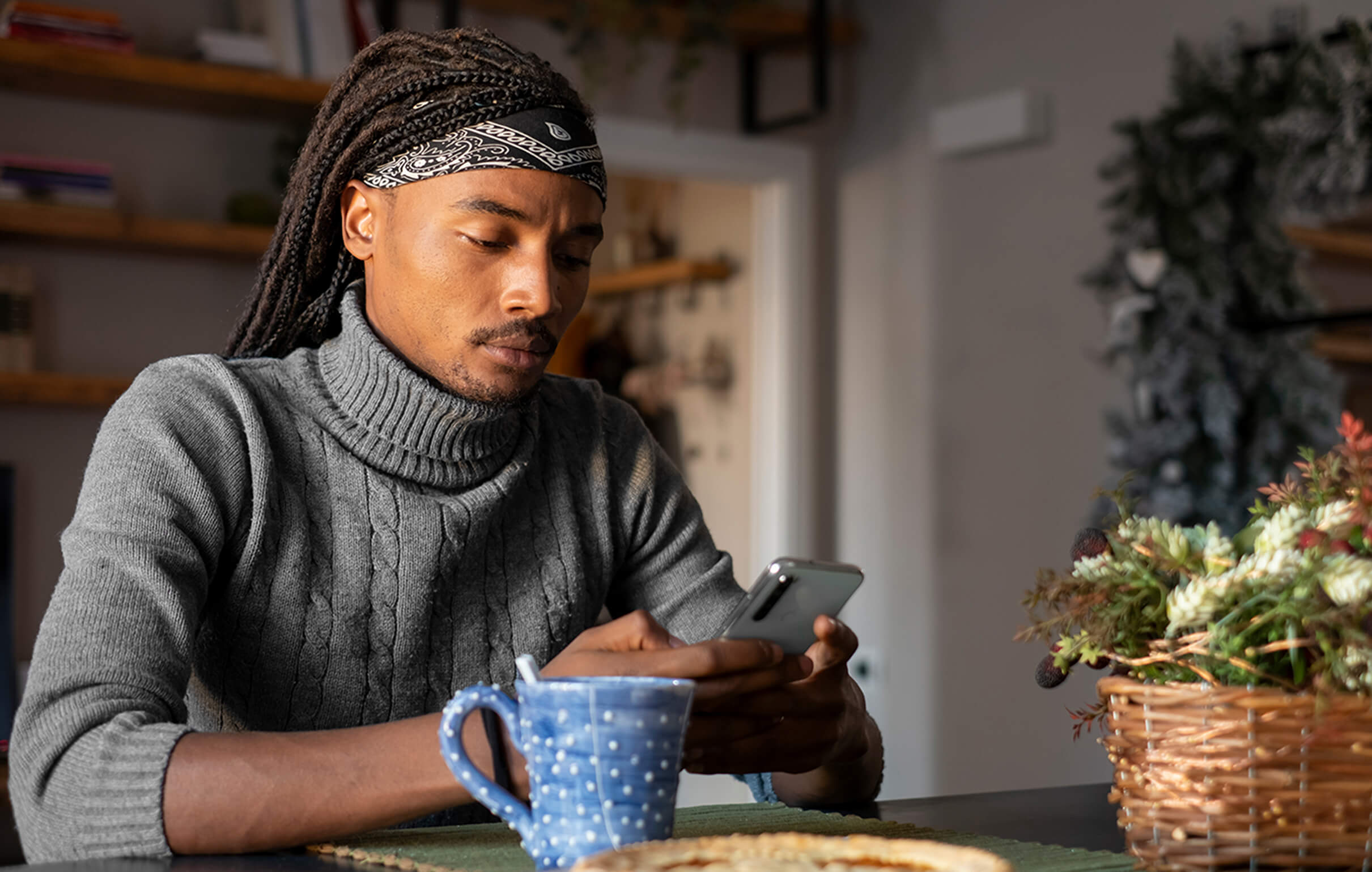 Male presenting person using phone at table