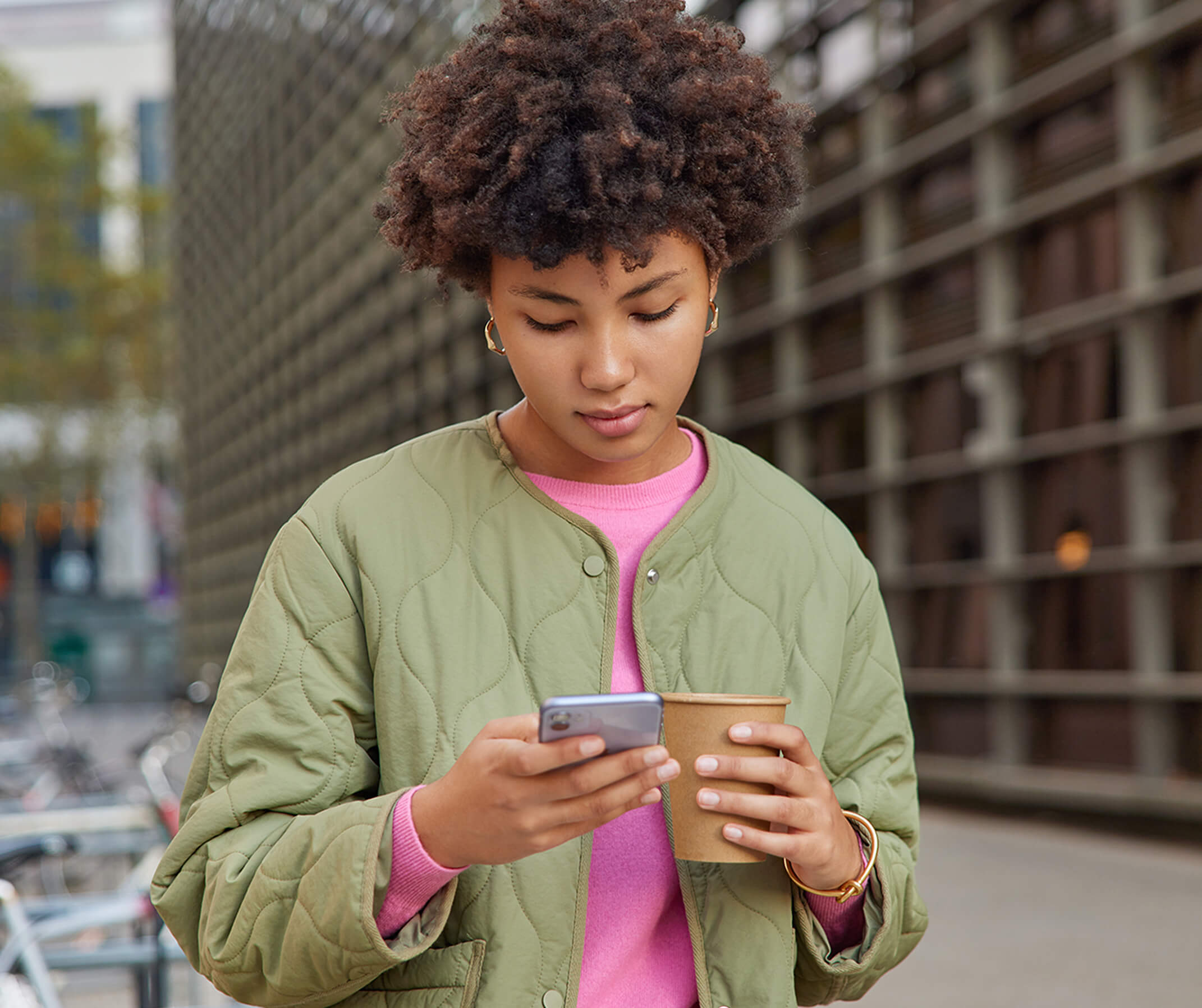 Curly haired female presenting person on phone outside