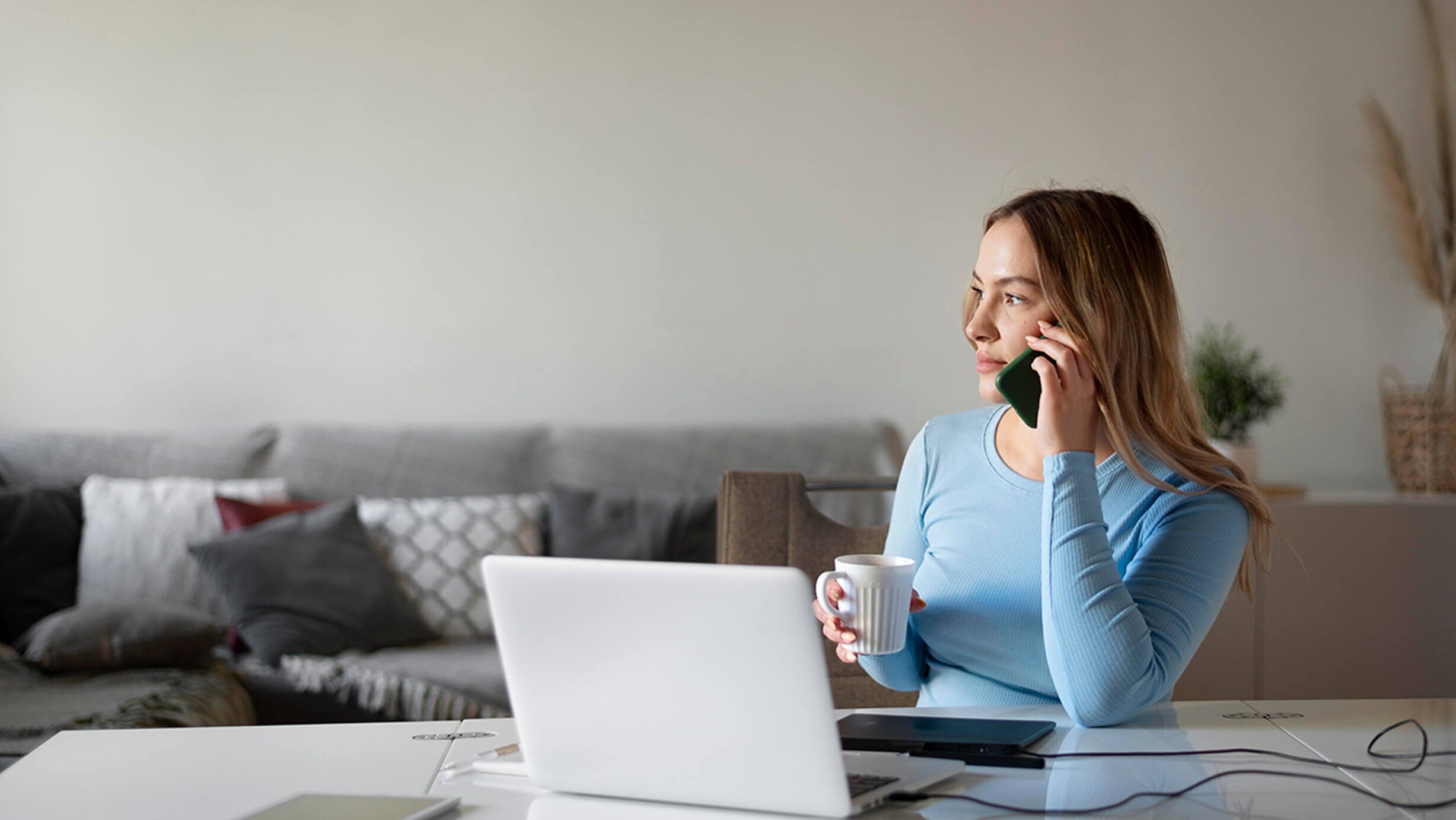 Female presenting person on phone whilst holding mug