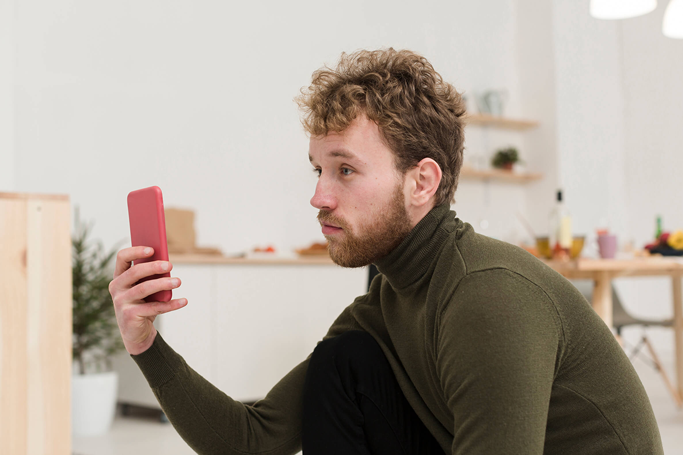 Male presenting person using phone at seat