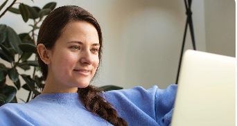 Female presenting person smiling at laptop