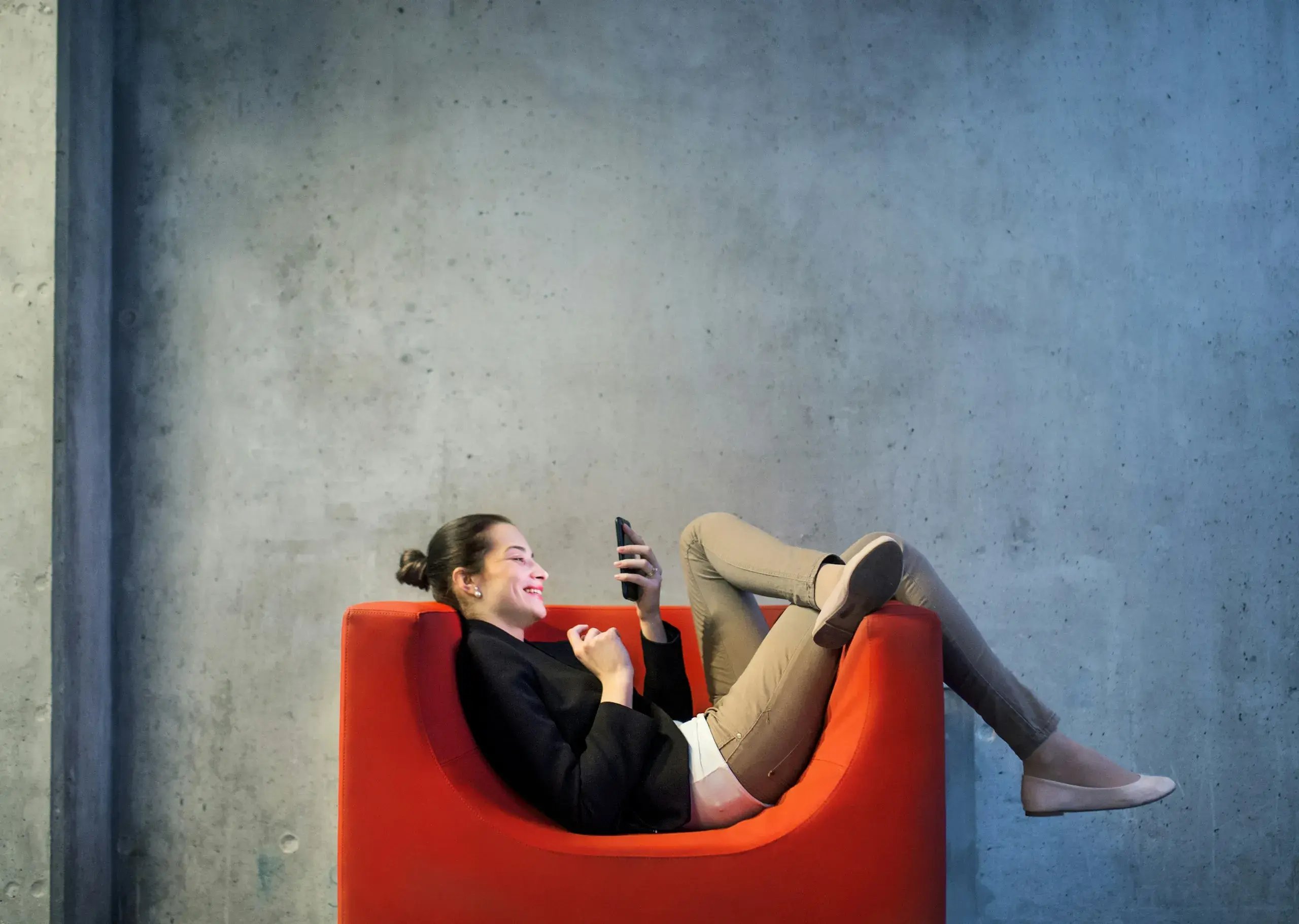 woman lying on chair smiling at phone