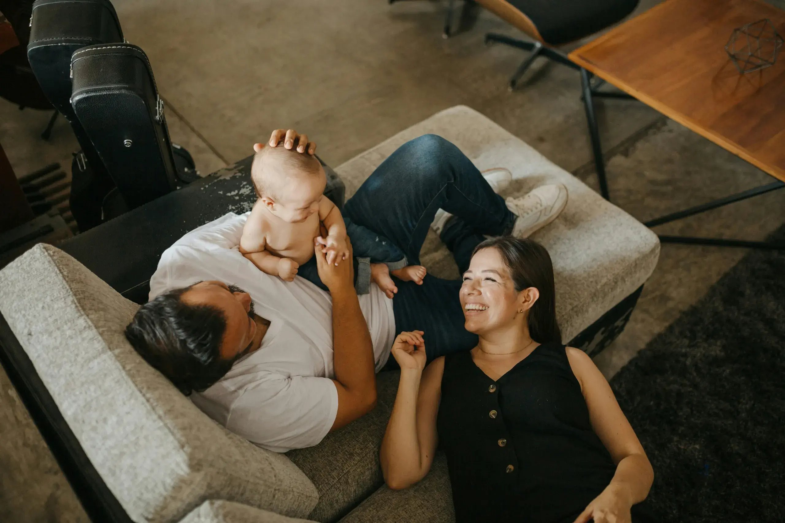 An overhead view of three friends laughing and relaxing together on a couch.