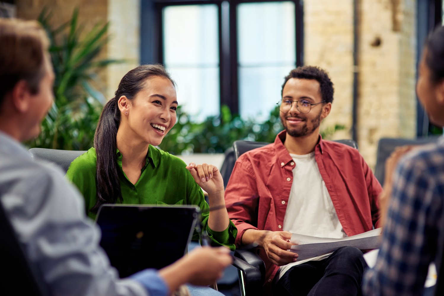 Young cheerful asian business woman discussing project results with colleagues while working together in the modern office
