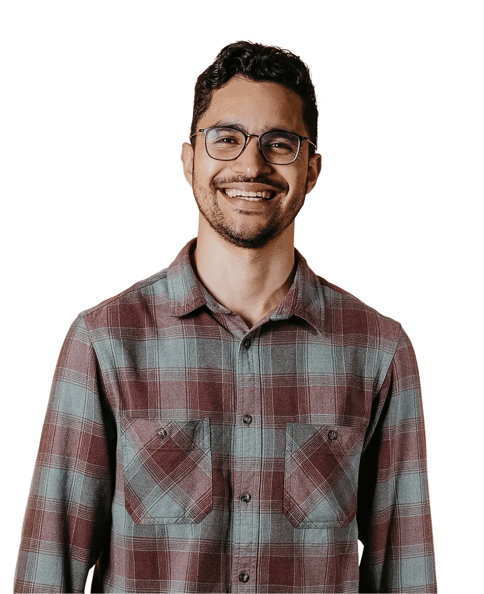 Man in a checked shirt with glasses and a beard against a light cream backdrop