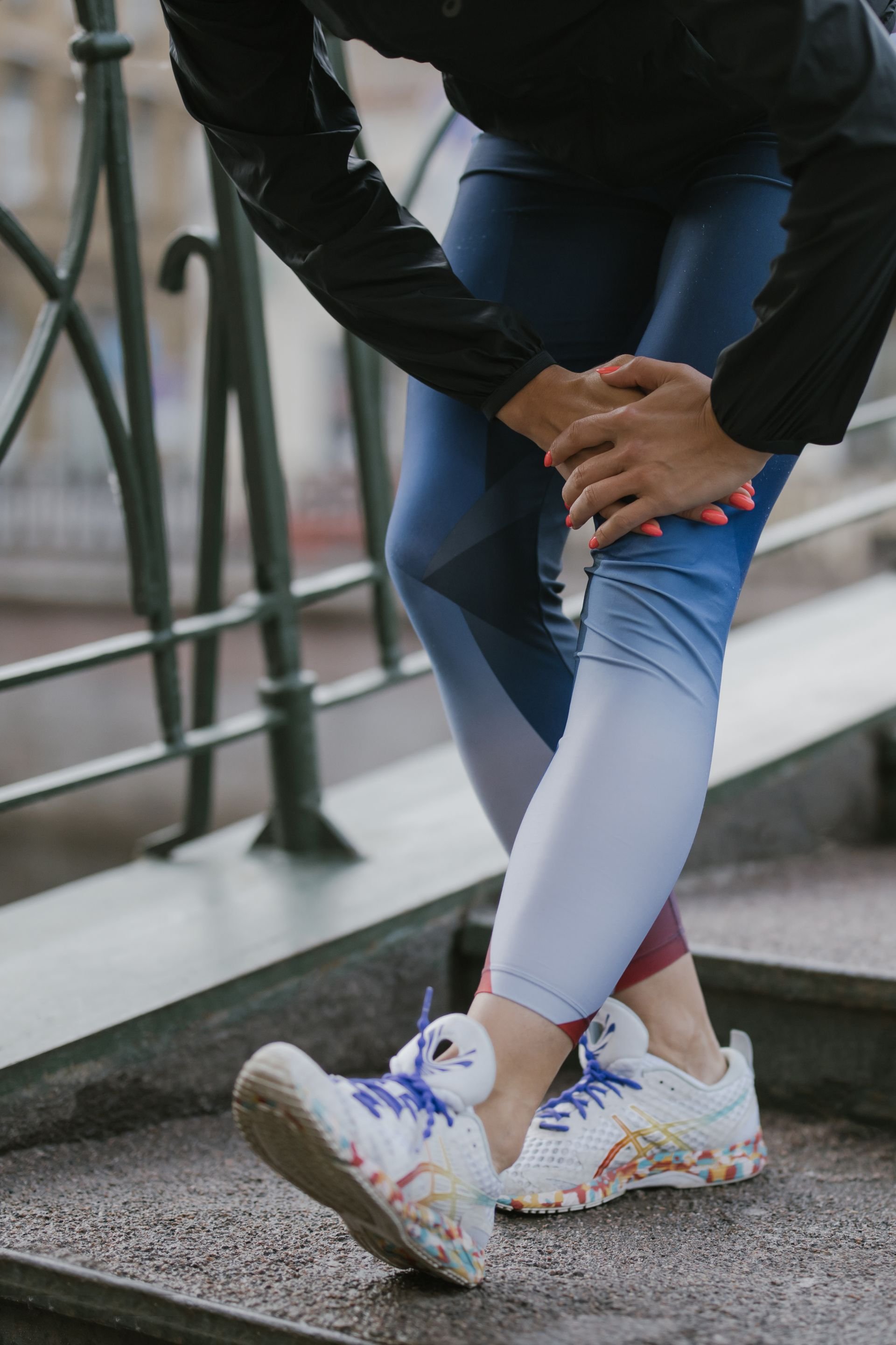 Close-up of a woman holding her thigh in pain while exercising outdoors