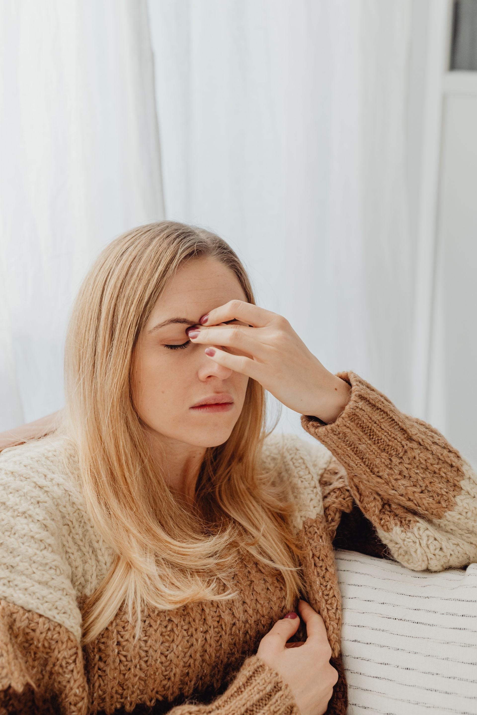Woman pinching the bridge of her nose with eyes closed, appearing to have a headache