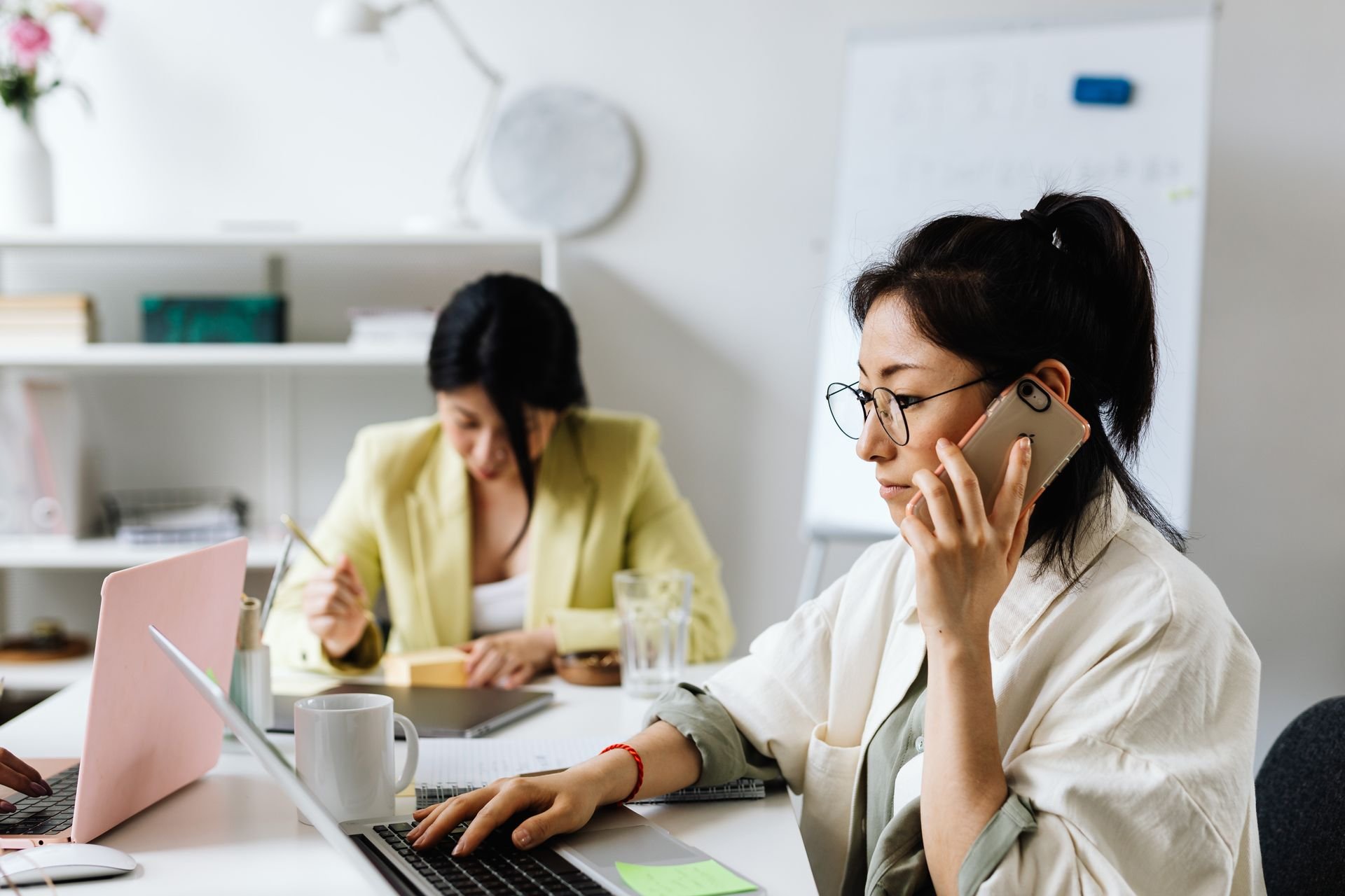 Two colleagues working together, one on the phone, next to text reading