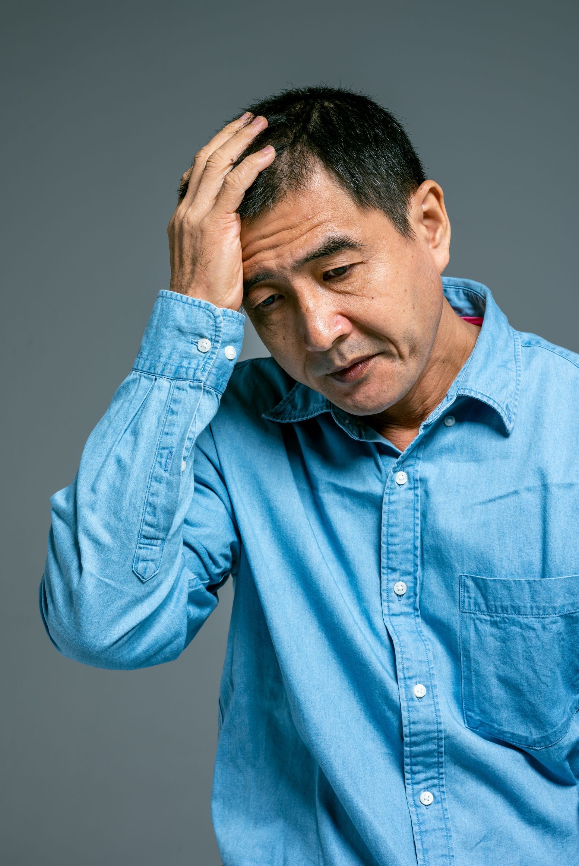 Man holding his head with a pained expression, appearing to have a headache