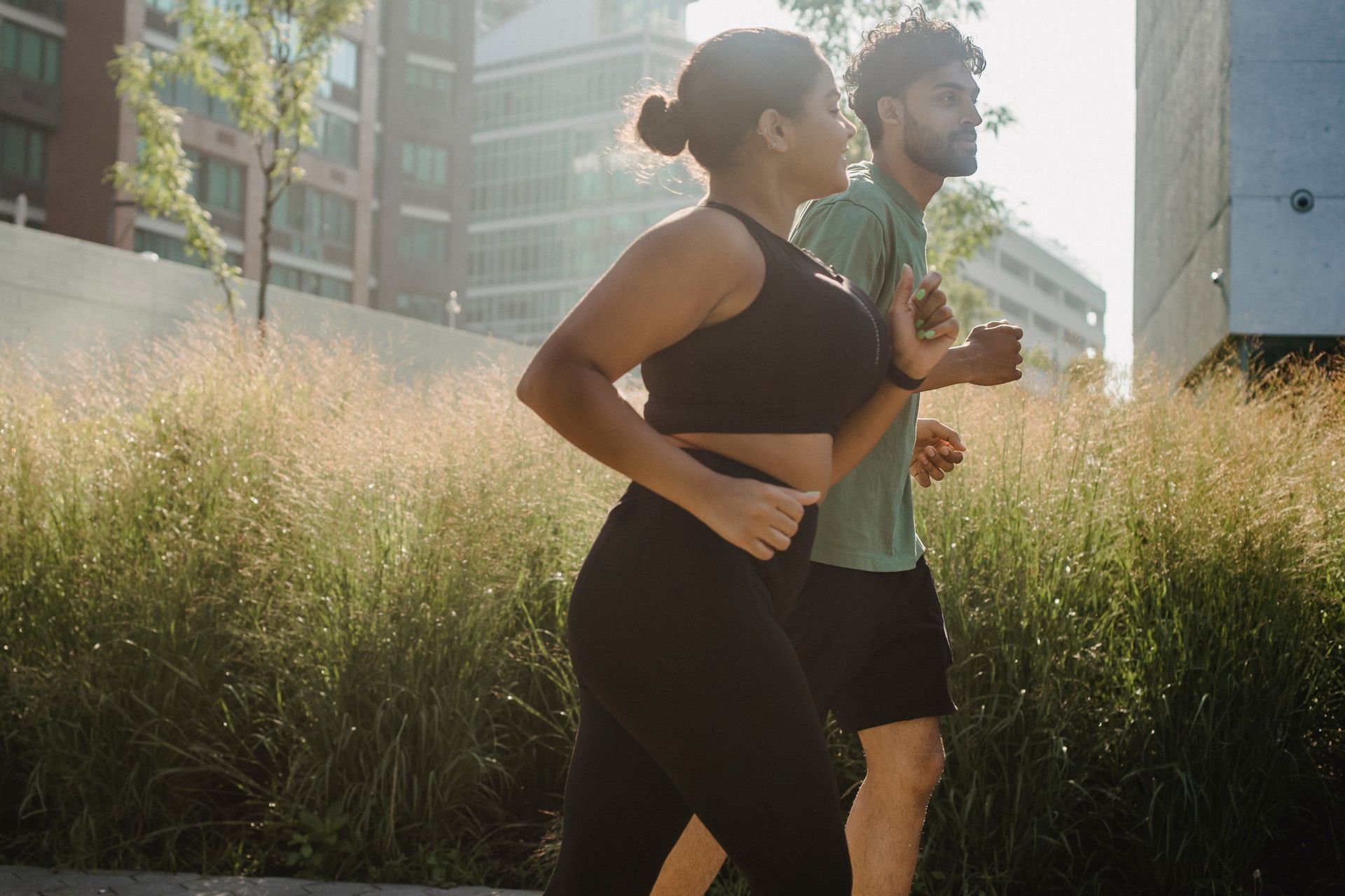 two people jogging together outdoors through tall grass