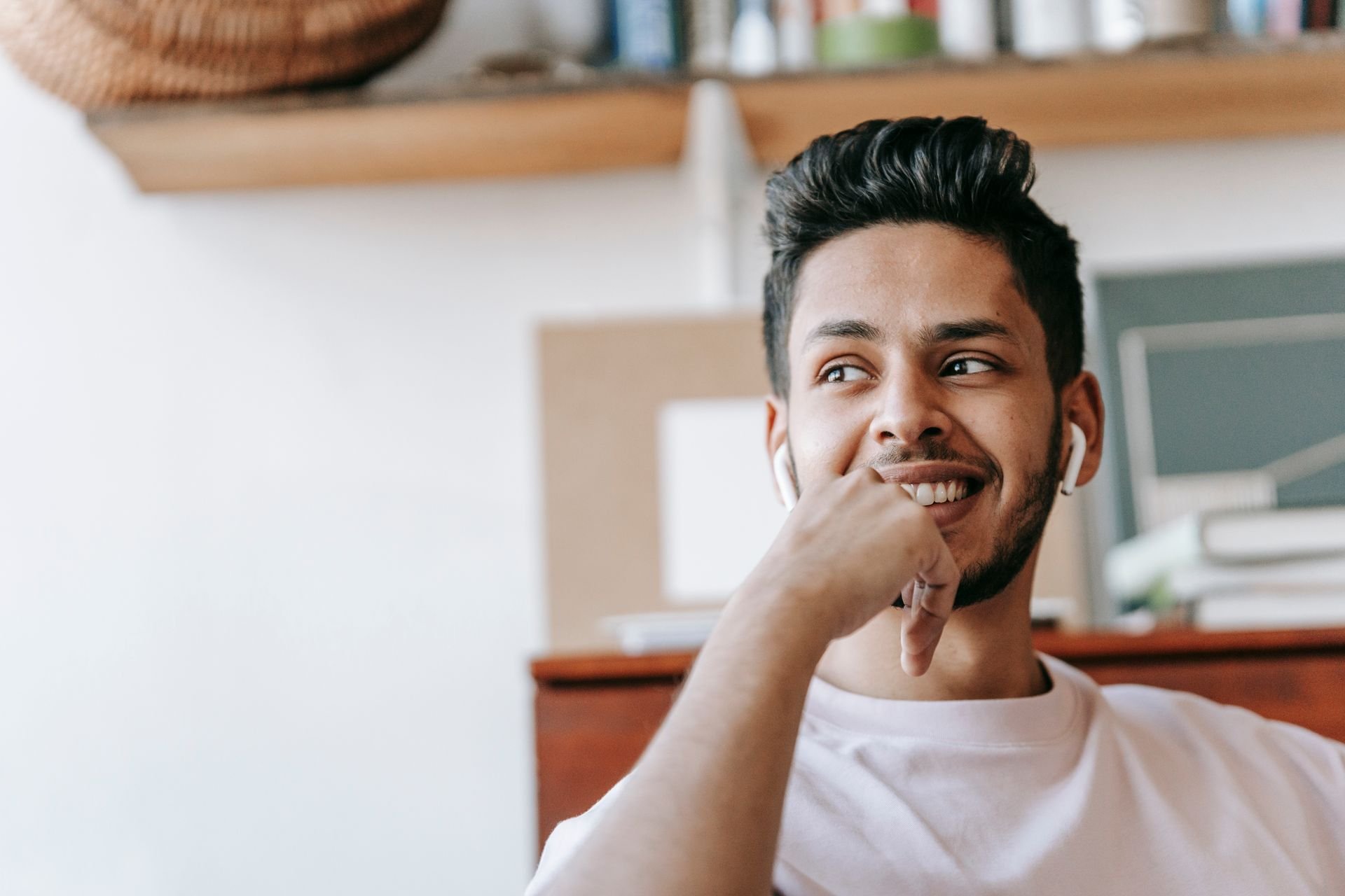 Smiling man wearing earphones biting his thumbnail while looking away