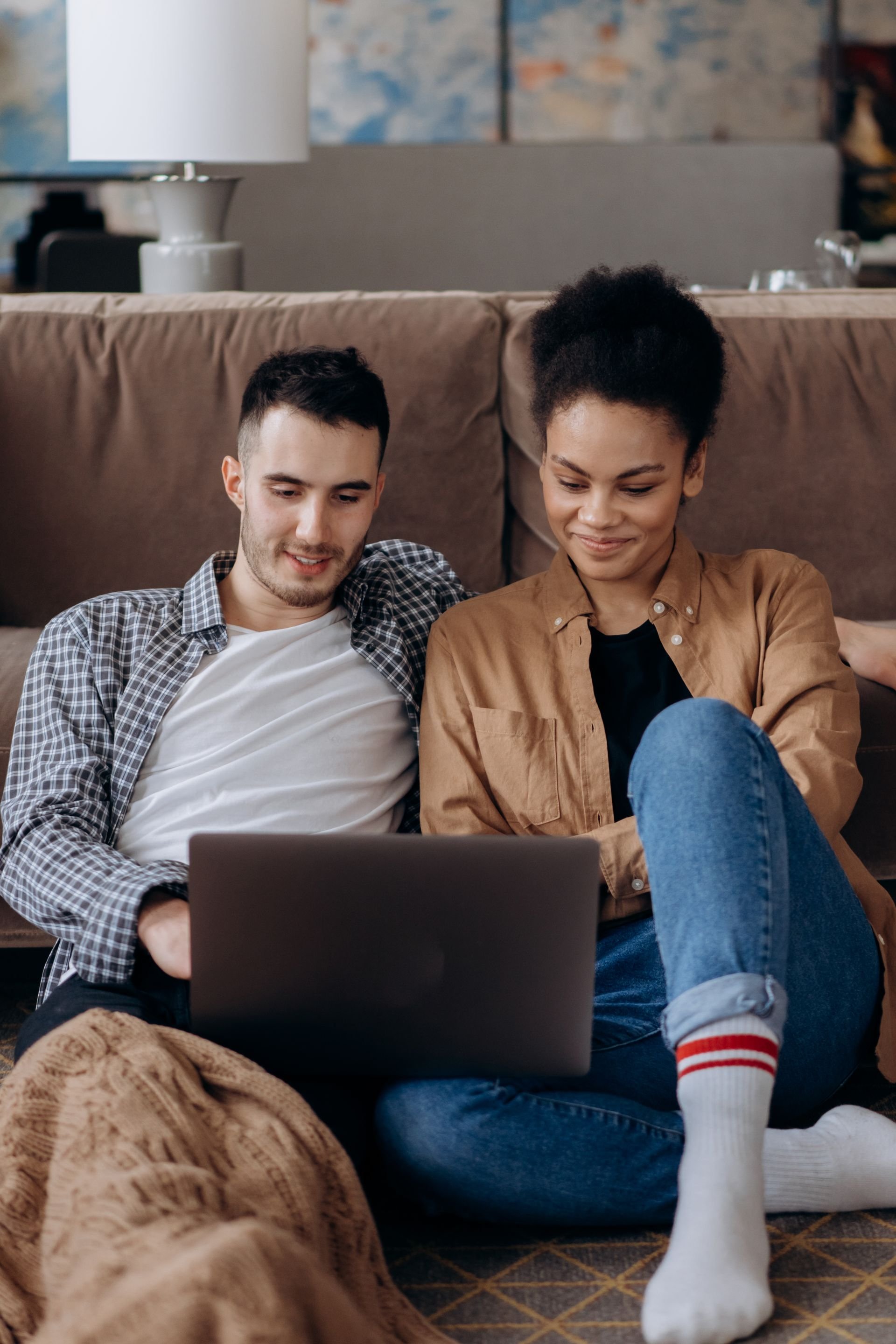 A young couple sitting together on a sofa, looking at a laptop screen. An orange 'Featured' badge is in the top right corner.