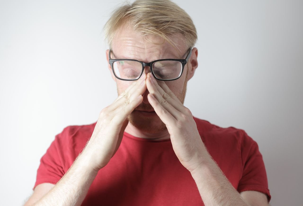 man in red top holding nose