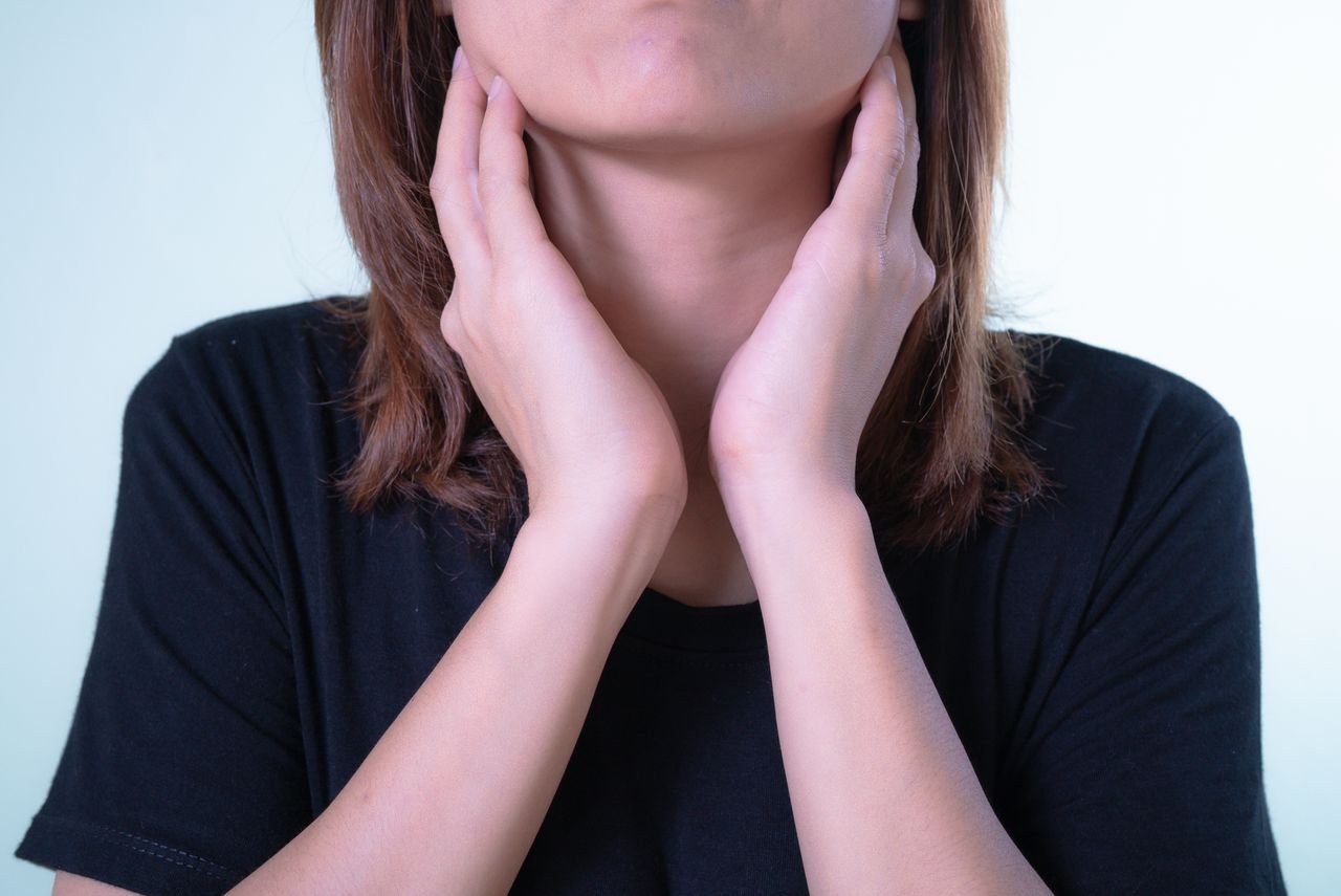 woman in t shirt feeling either side of neck