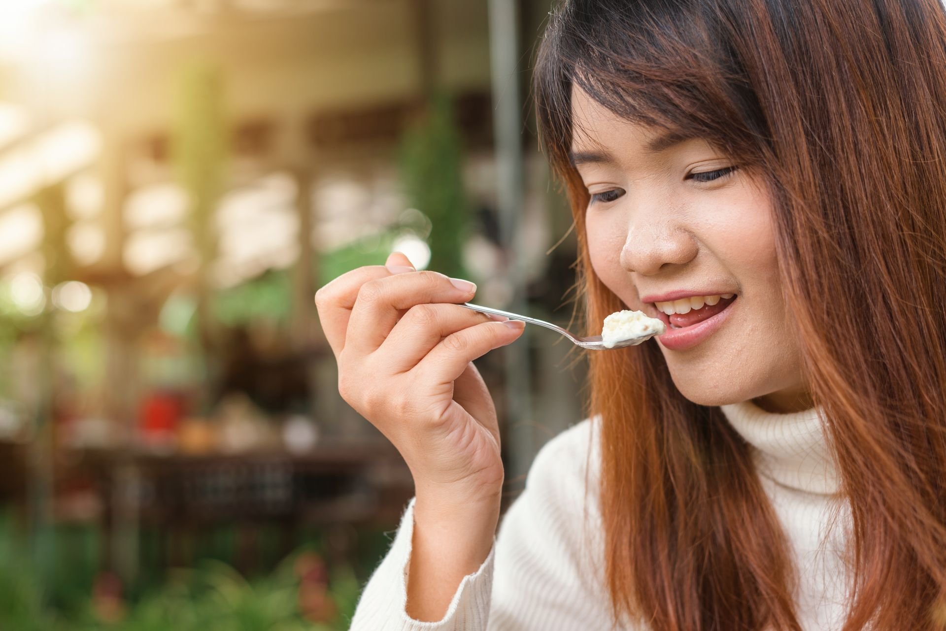 Woman eating a forkful of food outdoors
