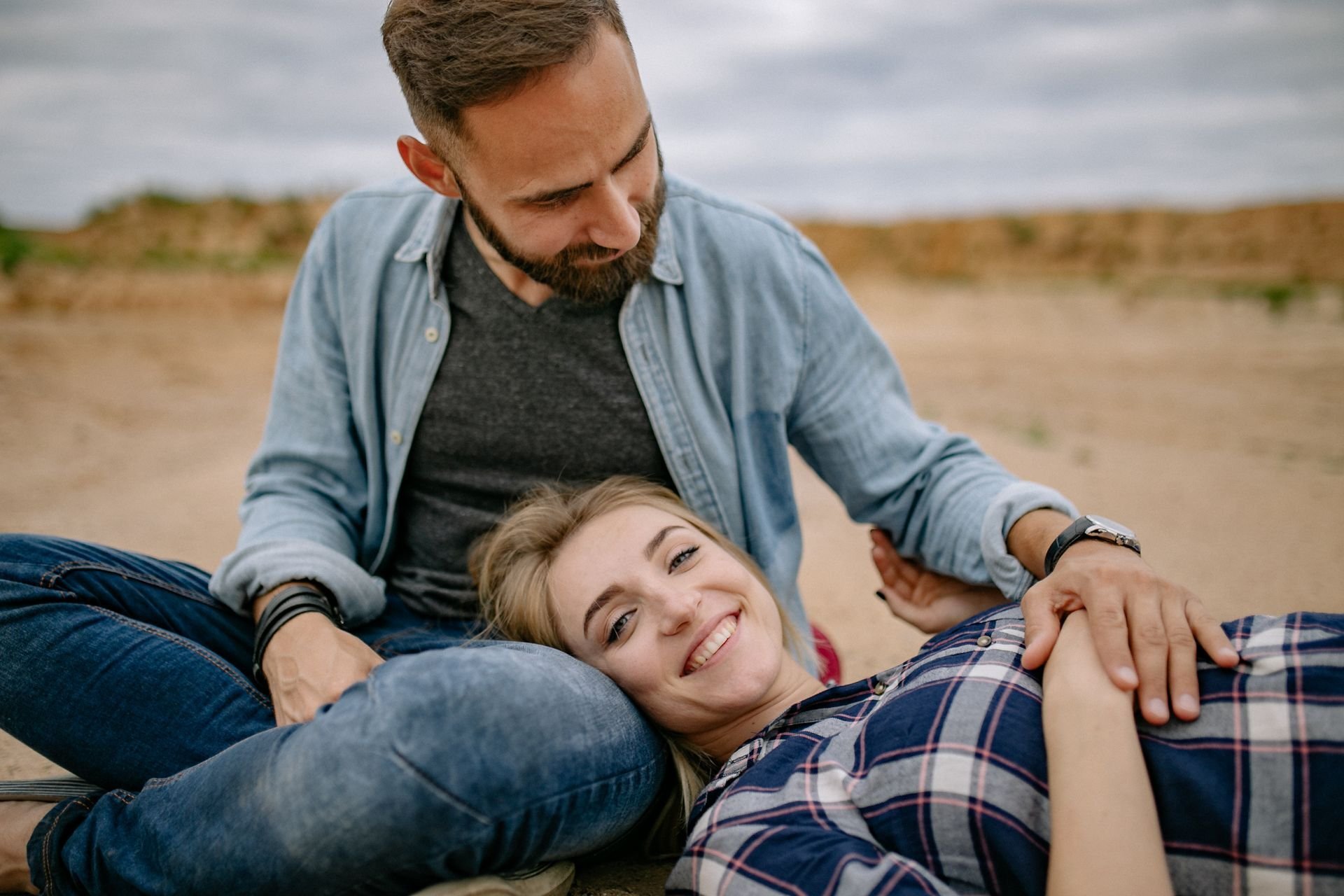 Smiling couple relaxing together outdoors, woman resting her head on the man's lap