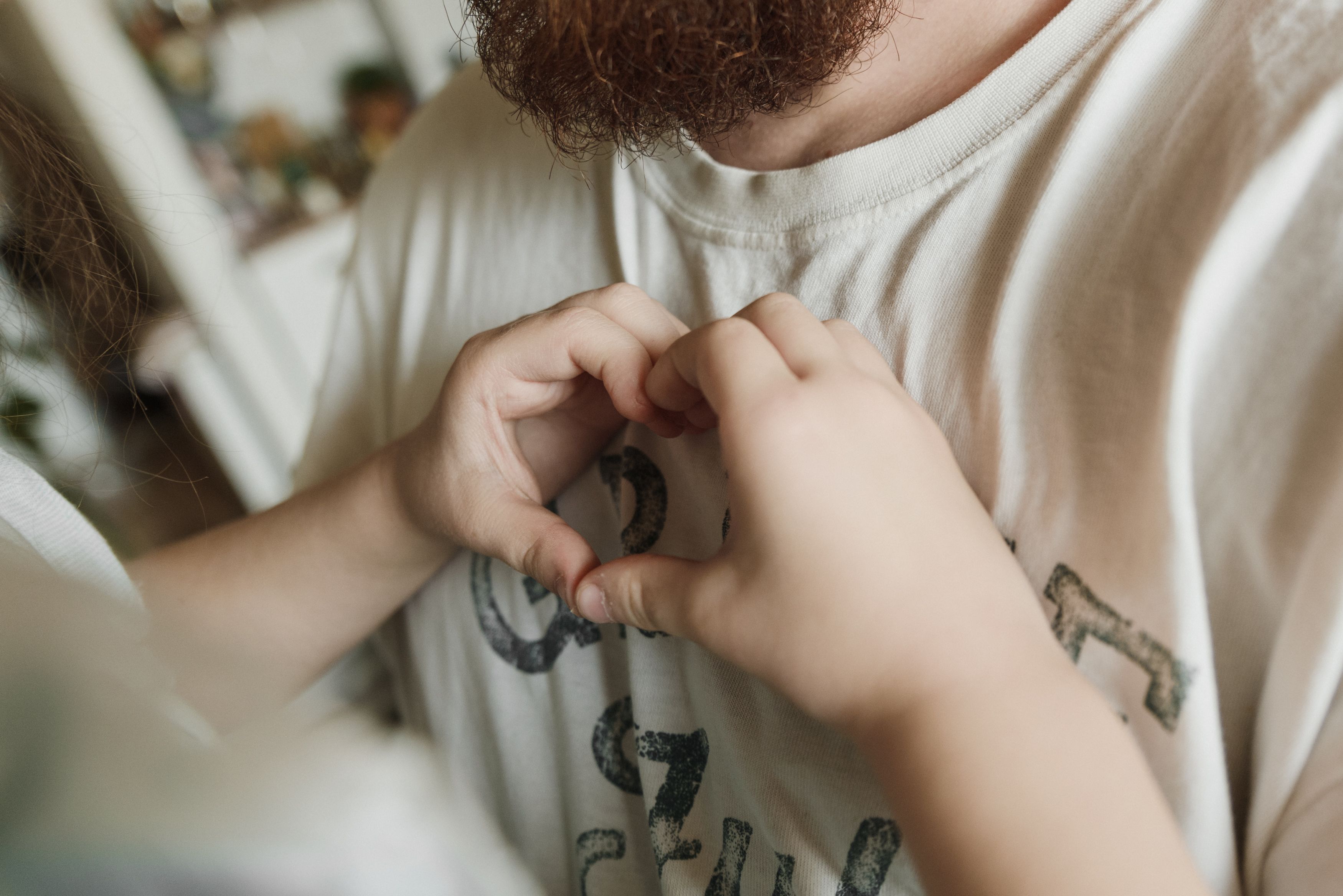 Close-up of a young child's hands fastening a button on their shirt, with a parent's hand assisting nearby. An orange 'Featured' badge is in the top right corner.
